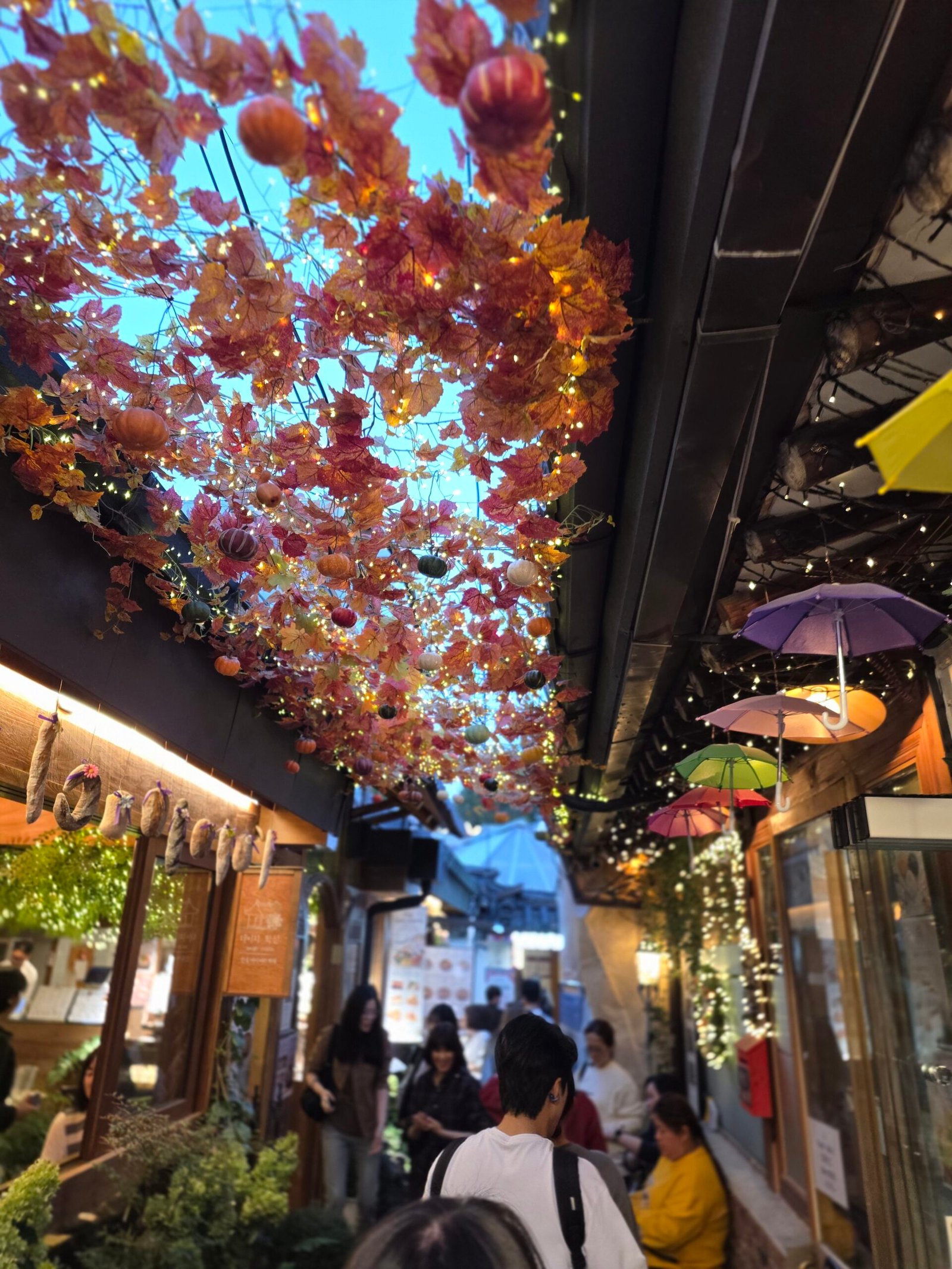 Autumn decorations and warm lights above a narrow Ikseon-dong alley.